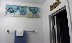 Ein Badezimmer mit Handtuchhalter, einem blauen Handtuch und drei Bildern von Meeresbewohnern an der Wand.