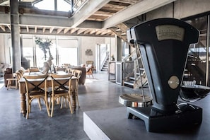 A modern interior with a coffee machine, wooden chairs, and a concrete floor.