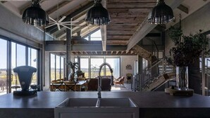 Una cucina moderna con una grande isola, illuminazione a sospensione e vista sull'esterno.