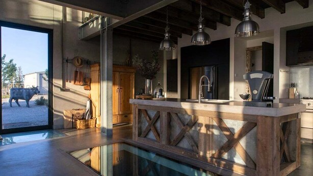 Una cucina moderna con isola centrale, illuminazione a sospensione e vista sull'esterno.