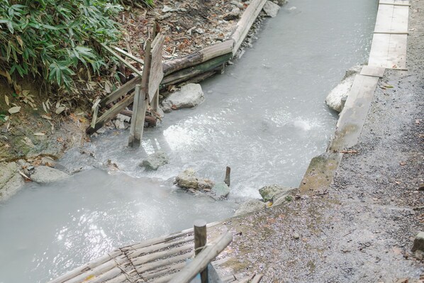A concrete pathway alongside a flowing stream with rocks and wooden barriers.