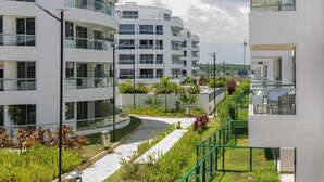 A modern multi-story building with balconies, a landscaped garden area, and a clear sky. - Apto moderno en Serena con balcon  (Cartagena)