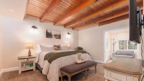 A bedroom with a bed, bedside tables, a bench, a table, and a fireplace. - Cozy Mountain Retreat, 5 Min Walk to  Downtown, Lake Membership, Sleeps 7 (Twain Harte)