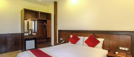 A hotel room with a large bed, a wardrobe, a desk, and a mirror.