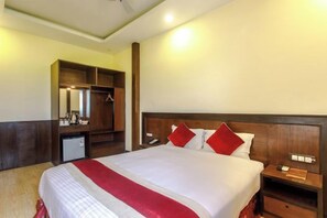 Una habitación de hotel con una cama grande, un armario, un escritorio y un espejo.