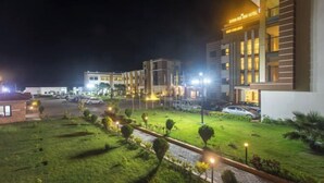 A hotel with a well-lit lawn, paved pathways, and multiple buildings with illuminated windows. - Bodhi Redsun (Rupandehi)