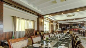 A formal dining room with long tables, chairs, and a bar area in the background. - Bodhi Redsun (Rupandehi)