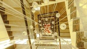 A spiral staircase with a central red and white design, surrounded by glass spheres and metal railings. - Bodhi Redsun (Rupandehi)