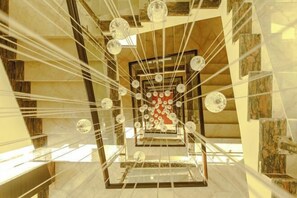 A spiral staircase with a central red and white design, surrounded by glass spheres and metal railings.