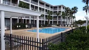 Ein Hotel mit Pool, mehreren Balkonen und Palmen.