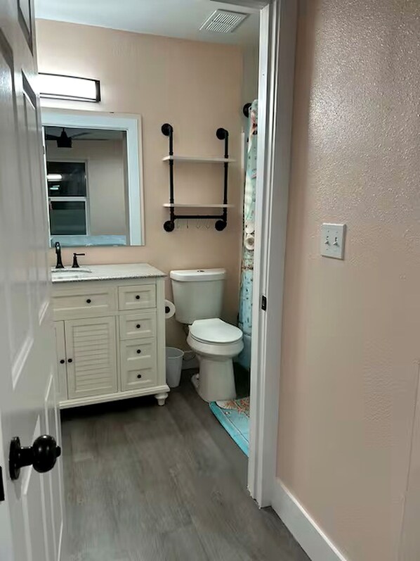 A bathroom with a toilet, a sink, a mirror, and a shelf above the toilet. - Adorable 1-bedroom condo steps from the beach in Perdido Key - Sleeps 6!! (Pensacola)