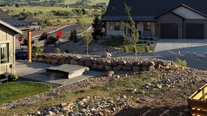 Ett bostadsområde med ett hus, en uppfart, en stenmur och ett berg i bakgrunden.