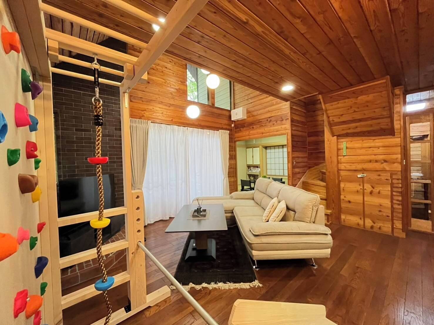 A wooden interior with a sofa, a climbing wall, and a dining area.