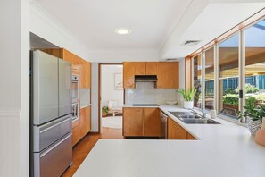 A modern kitchen with wooden cabinets, stainless steel appliances, and a large window offering a view of the outdoors.