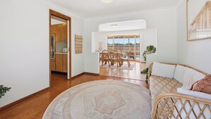 A spacious living area with a dining table, a sofa, and a view of the outdoors.