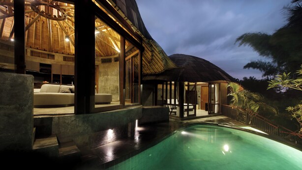 Una casa moderna con piscina, ventanas amplias y techo de paja.