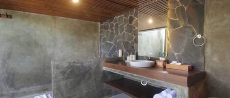 A bathroom with a stone wall, wooden ceiling, and a built-in sink with a mirror.