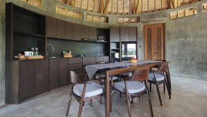 Una cocina con techo curvo, armarios de madera, una mesa de comedor con sillas y vistas por una ventana.