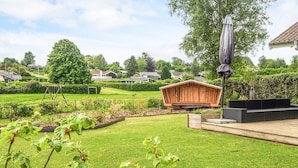 En velholdt have med et trækonstruktion, et siddeområde og en pergola.
