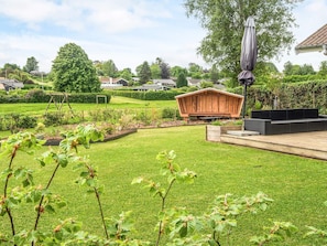 Ein gepflegter Garten mit einer Holzkonstruktion, einer Sitzgelegenheit und einer Pergola.
