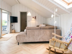 Ein gemütliches Zimmer mit einer Couch, einem Holzstuhl, einem Fernseher und einer Deckenleuchte.