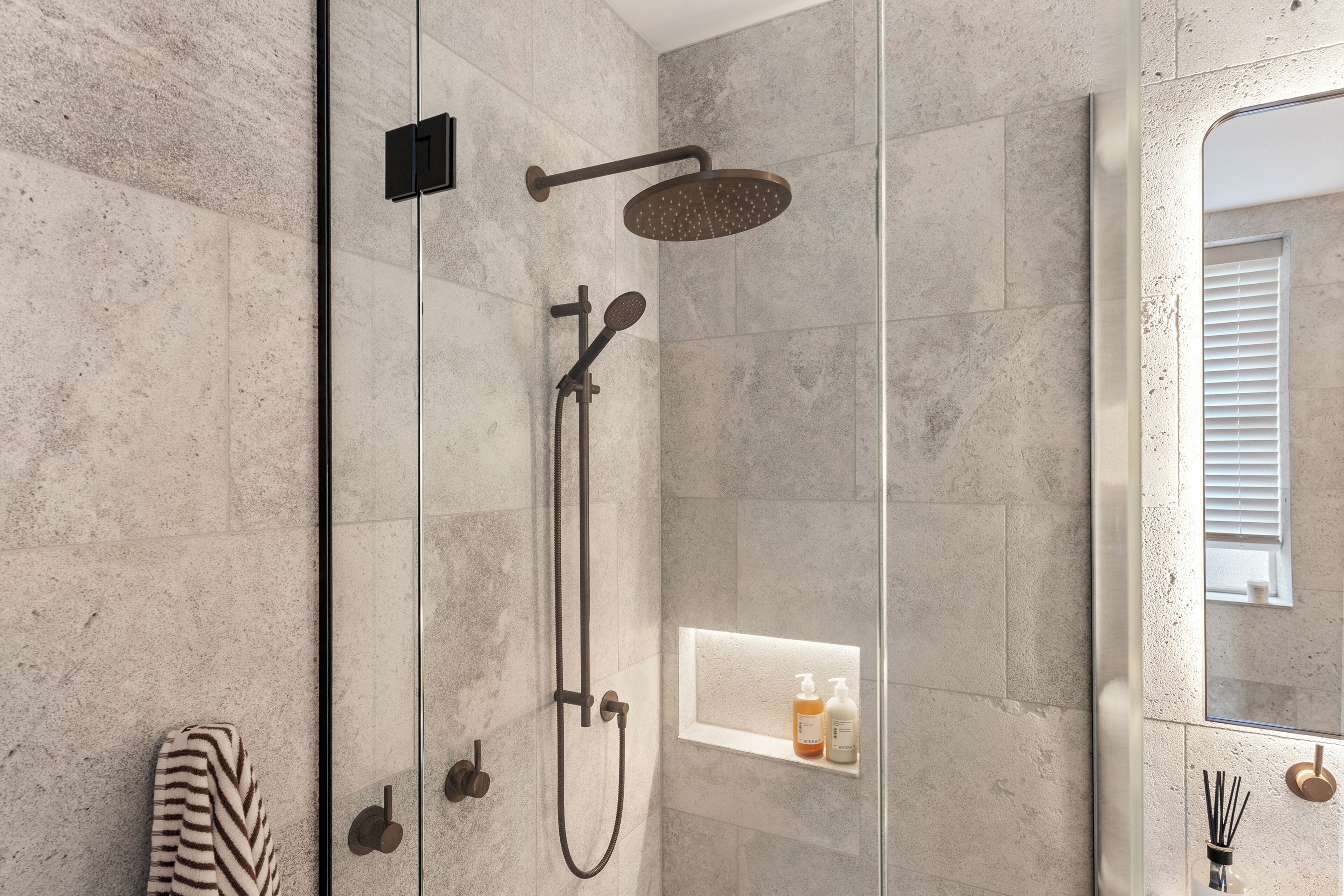 Eine moderne Dusche mit Handbrause, einer fest montierten Bedienarmatur und einem Glasduschaumraum.