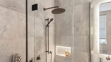 Eine moderne Dusche mit Handbrause, einer fest montierten Bedienarmatur und einem Glasduschaumraum.