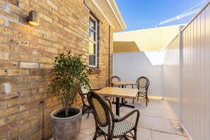 Un patio con pared de ladrillo, planta en maceta y una mesa con sillas.