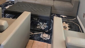 A living room with a sectional sofa, a coffee table, and a patterned rug.
