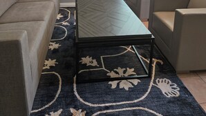 A living room with a sofa, armchair, coffee table, and patterned rug.