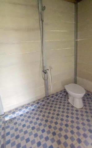 A bathroom with a checkered floor, a toilet, and a shower. - Tanjung Kalemo Resort (Tojo una-una, Sulawesi Tengah)