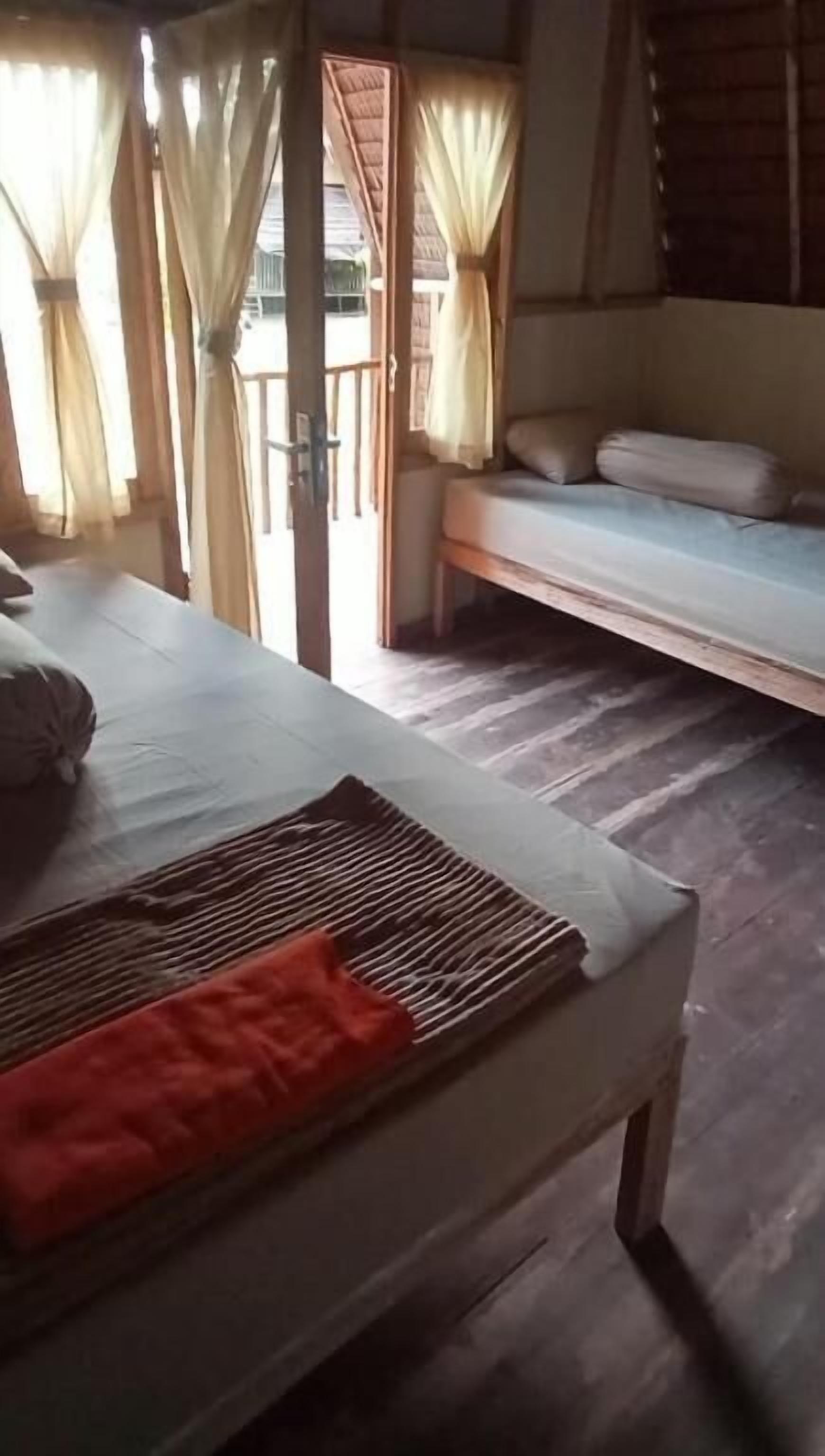 A room with a bed, a bench, and a table with a mat.