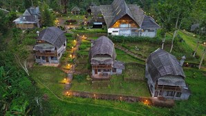 Un conjunto de edificios de estilo tradicional con techos de paja, rodeado de exuberante vegetación y un sendero sinuoso.