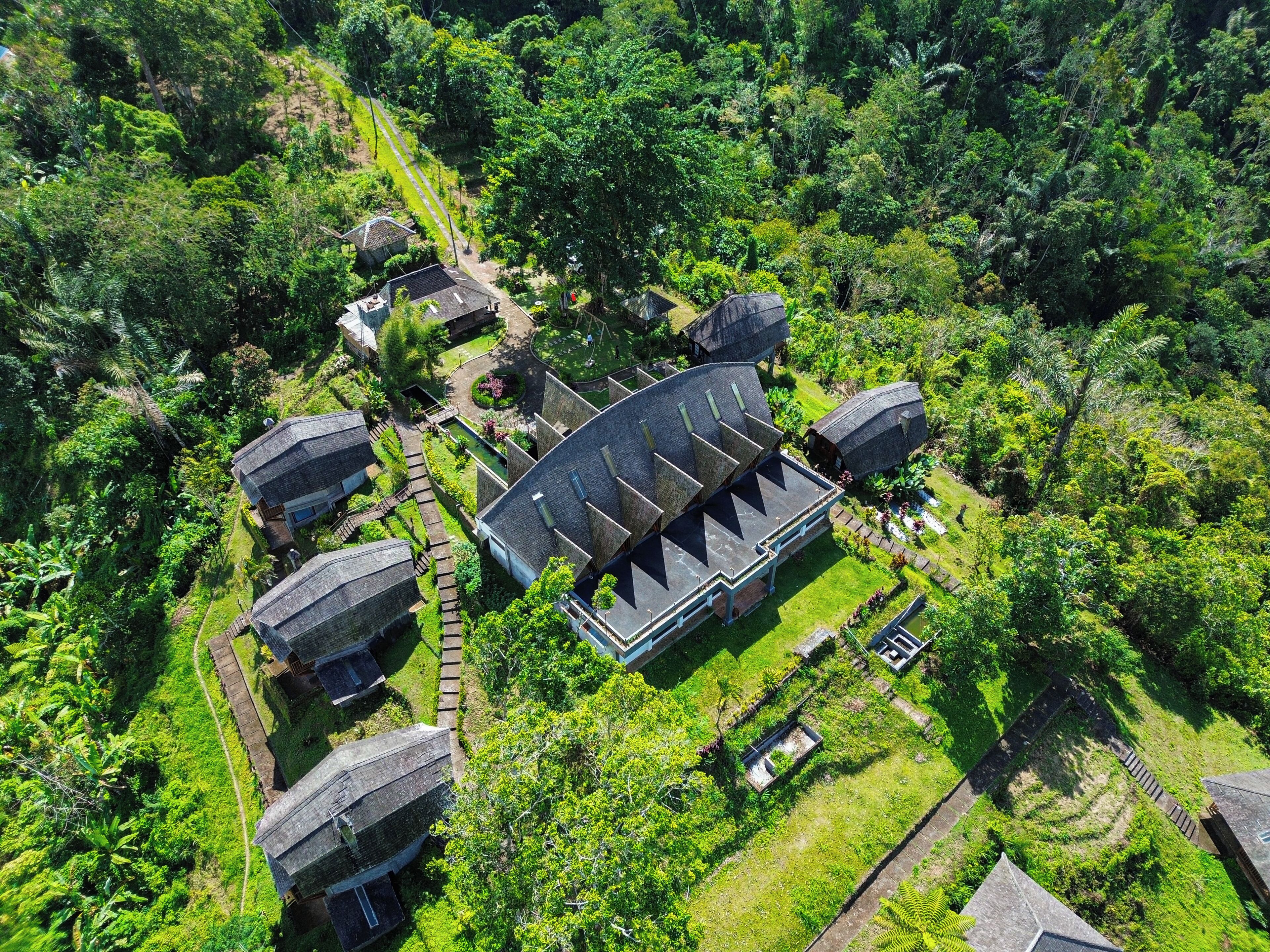 Vista aérea de un complejo de edificios tradicionales rodeado de abundante vegetación.