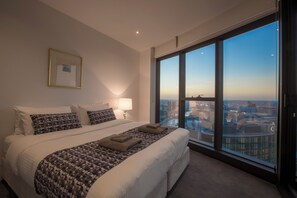 A hotel room with a large bed, a city view, and a framed picture on the wall. - Exclusive Stays - Prima Tower (Southbank)