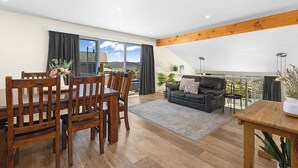 Un vaste espace de vie comprenant une salle à manger avec table et chaises, un canapé et un balcon offrant une vue sur le paysage.