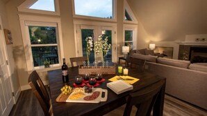 A dining area with a table set for four, a bottle of wine, and a variety of food items. - Bright Loft Near Wineries & Park | Sleeps 6 (College Place)