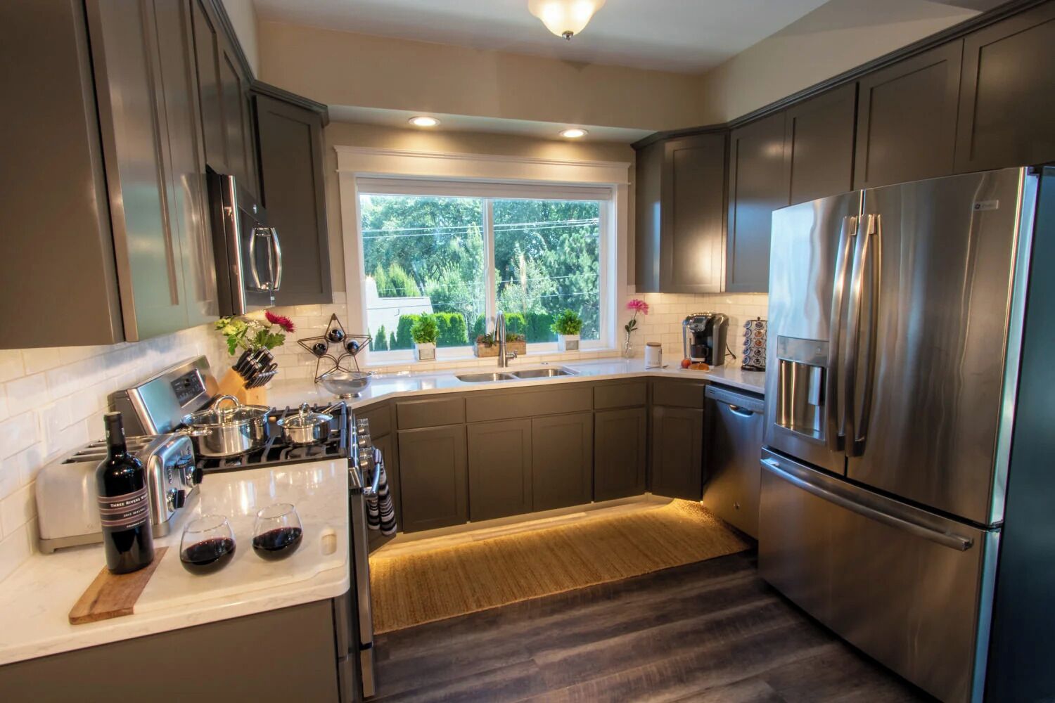 A modern kitchen with stainless steel appliances, a window with a view of greenery, and a built-in oven.