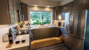 A modern kitchen with stainless steel appliances, a window with a view of greenery, and a built-in oven.