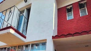 Ein zweistöckiges Gebäude mit Balkon, großen Fenstern und einem Schild, auf dem 'willkommen in unserem HOME' steht.