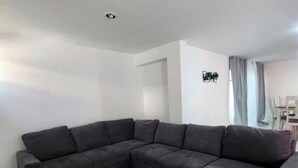 Ein L-förmiges Modulsofa in einem Raum mit weißen Wänden und Fliesenboden.