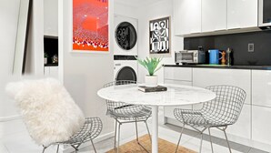 Una cucina moderna con mobili bianchi, un tavolo rotondo con sedie in metallo e una poltrona bianca e soffice.