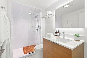 Un baño moderno con cabina de ducha de vidrio, un lavabo blanco y un espejo encima.
