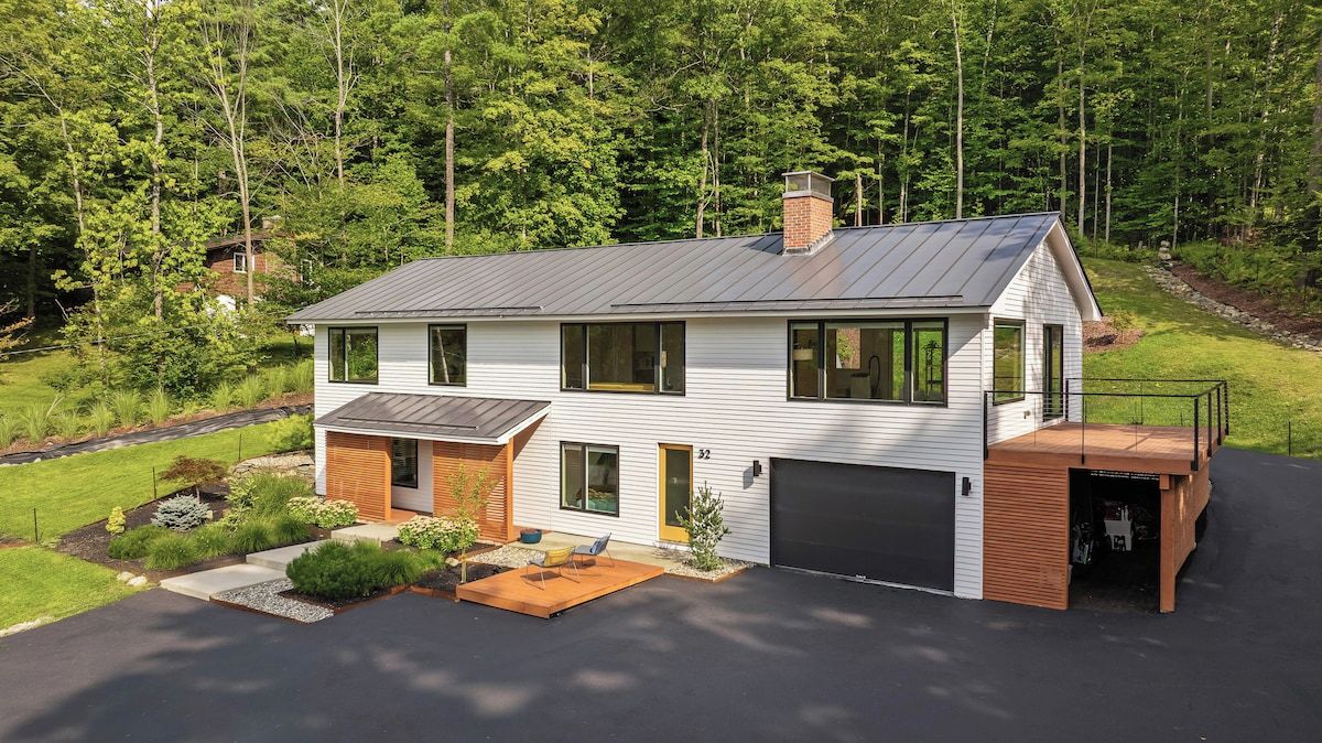 A modern two-story house with a garage, a covered porch, and a landscaped front yard.