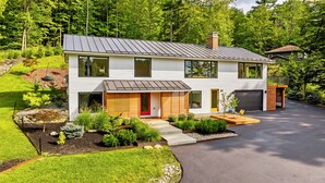 Una moderna casa a due piani con tetto spiovente, un portico e una strada privata.
