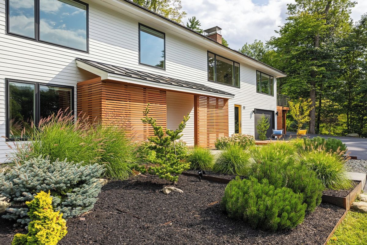 Une maison moderne à deux étages avec un jardin aménagé.