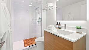 Un bagno moderno con box doccia in vetro, lavandino bianco e specchio sopra.
