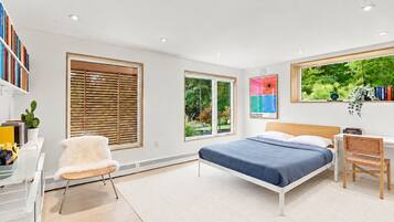 Une chambre moderne avec un lit, un bureau, une chaise et de grandes fenêtres.