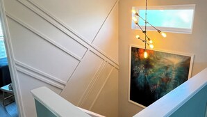 Una escalera con barandilla blanca, un cuadro en la pared y una guirnalda de luces.