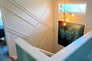 Eine Treppe mit weißer Handläufung, ein Gemälde an der Wand und eine Lichterkette.